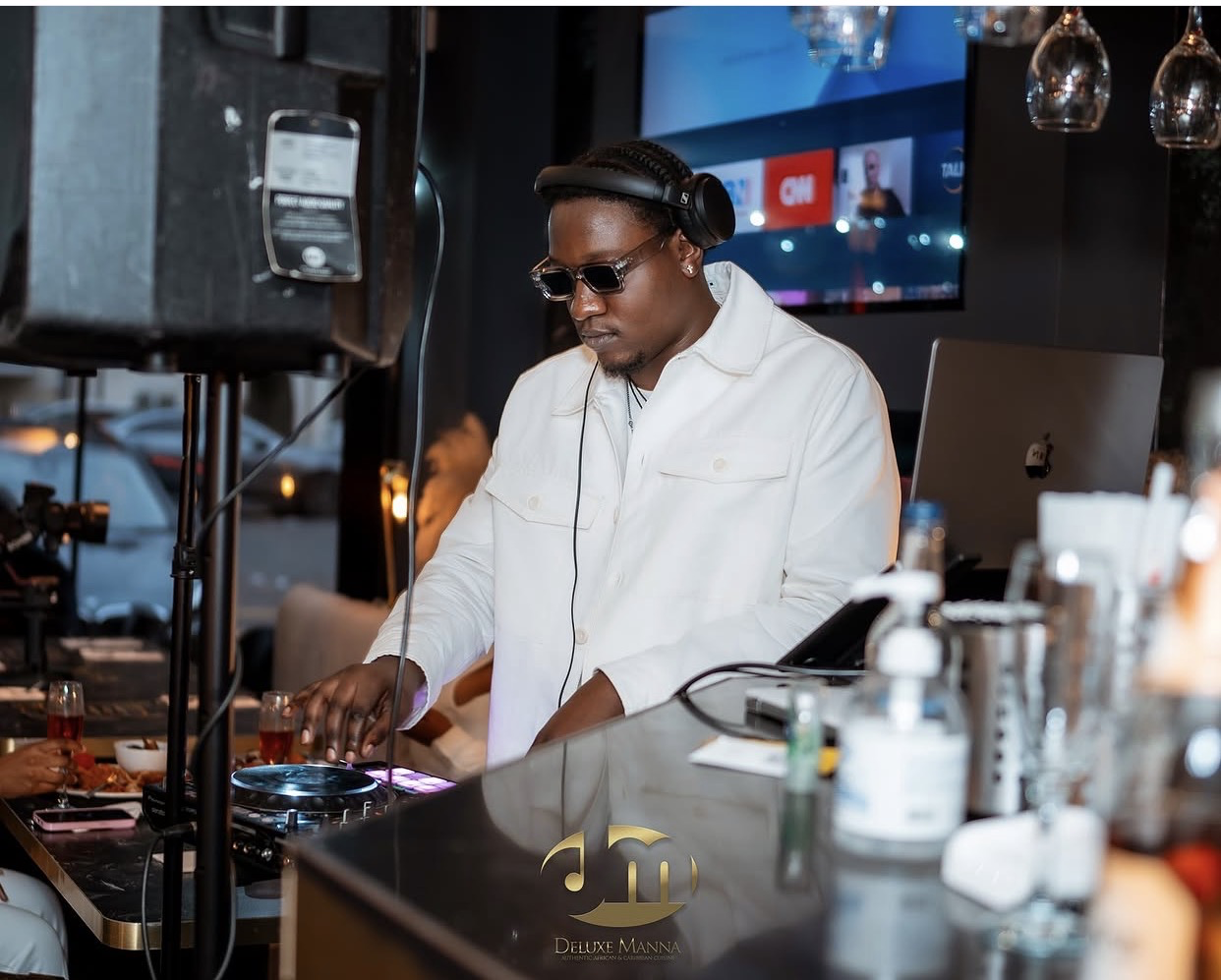 A DJ in a white jacket setting the music for a Deluxe Manna event